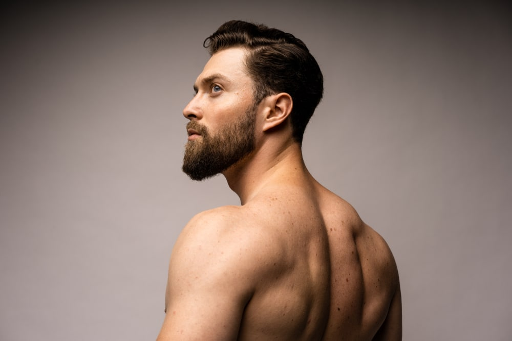 Man shown from the side and back, shirtless