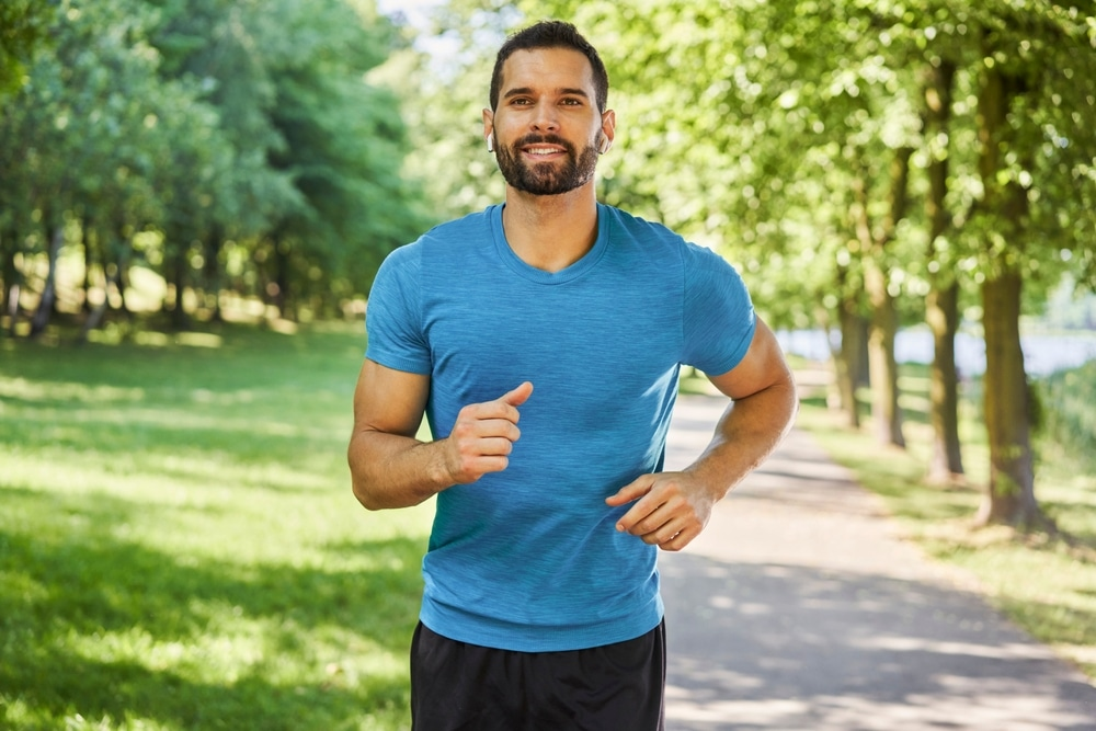 Man jogging outdoors in a park wearing a blue shirt