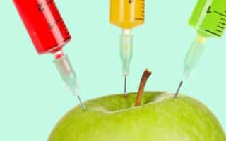 Illustration of three colorful syringes injecting into a green apple