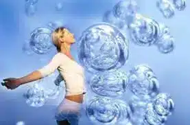Woman with arms outstretched surrounded by bubbles, representing wellness