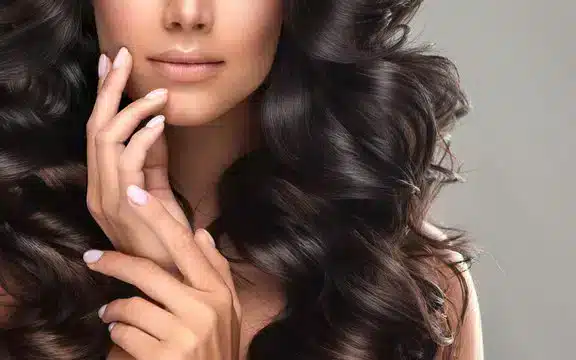 Woman with long wavy hair touching her face