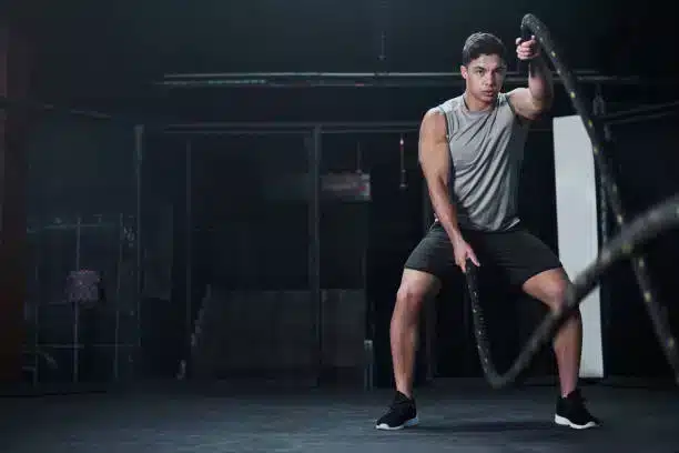 Man exercising with battle ropes in a gym