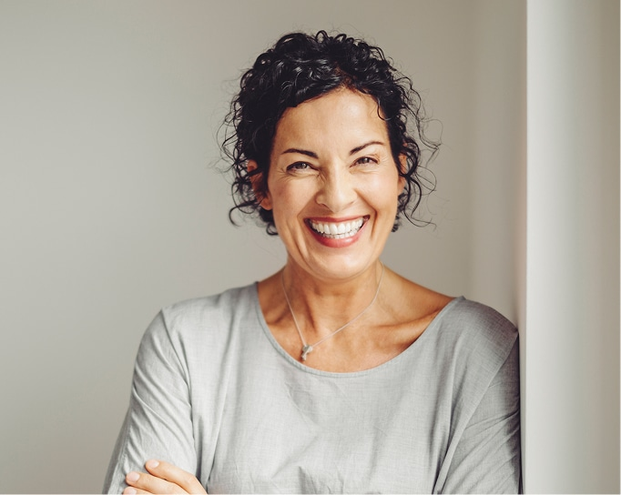 Woman with curly hair smiling with arms crossed
