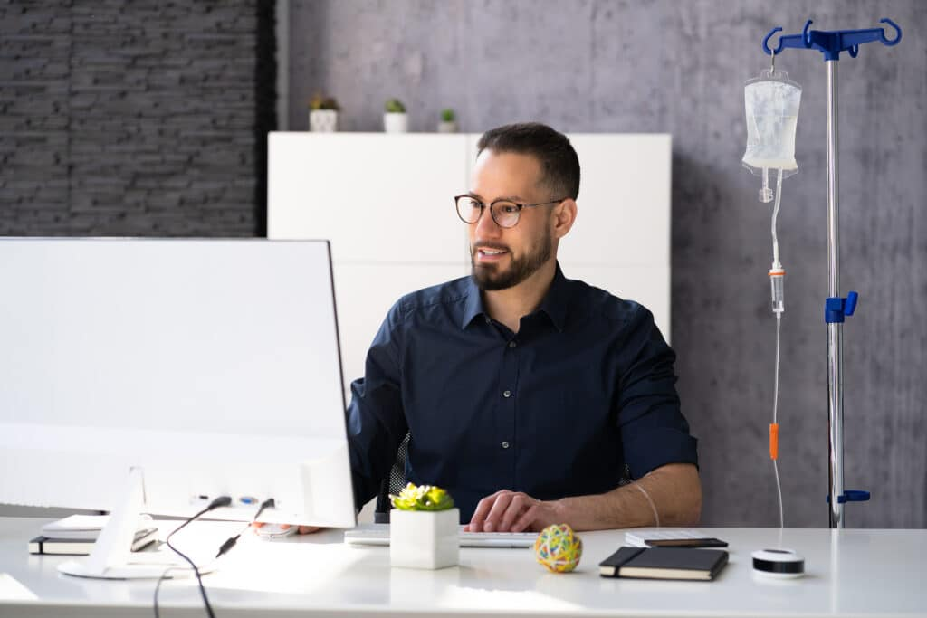 Man sitting at a table with an IV stand nearby