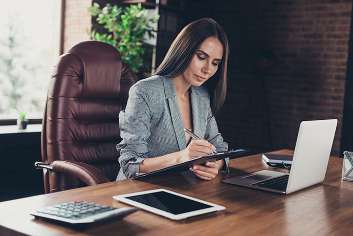 Woman working at a desk with a laptop and tablet