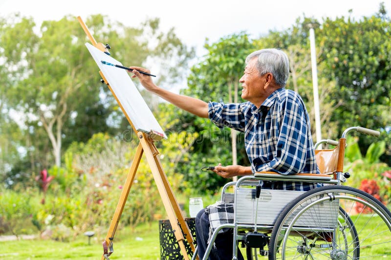 Older man in a wheelchair painting on an easel outdoors