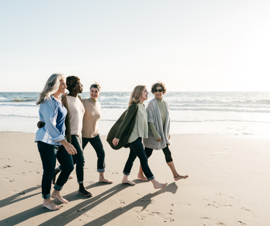 Group of four women walking together along a beach