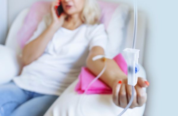 Woman receiving an IV drip while seated, holding her head