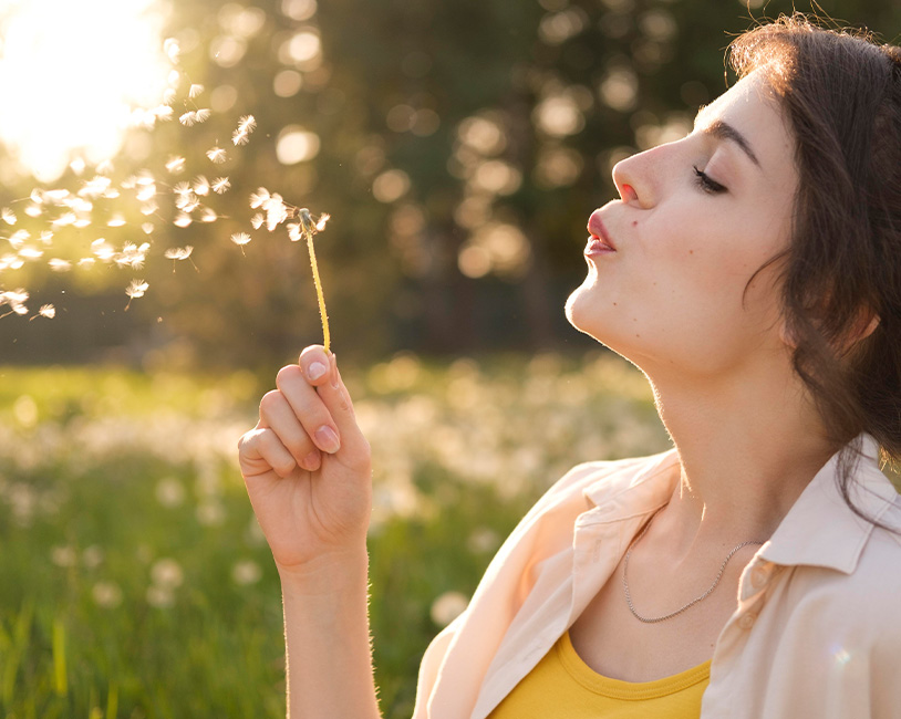 photo of a woman blowing on a dandelion