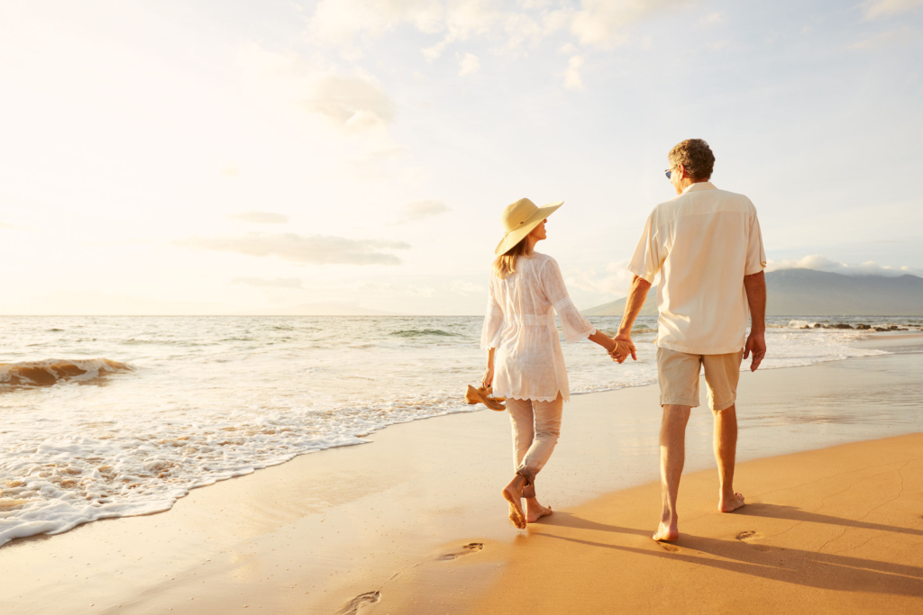 photo of a man and woman walking hand in hand on a beach
