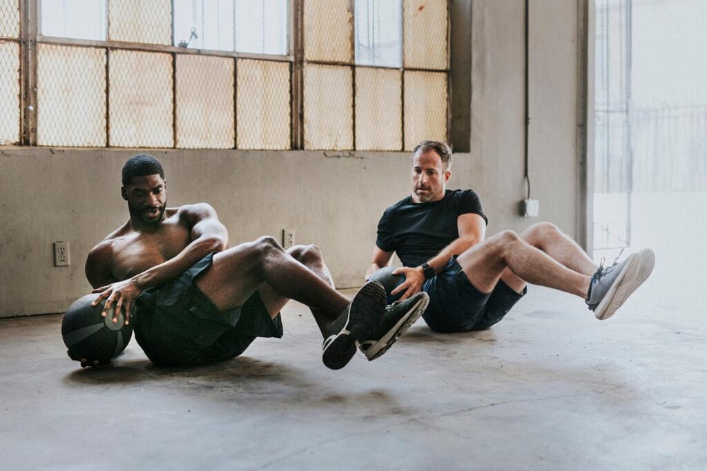 Two men sitting on the floor stretching during a workout