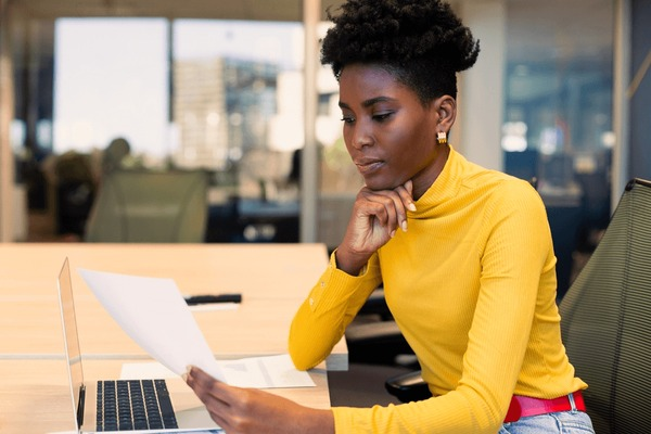Woman looking thoughtfully at papers while sitting at a desk