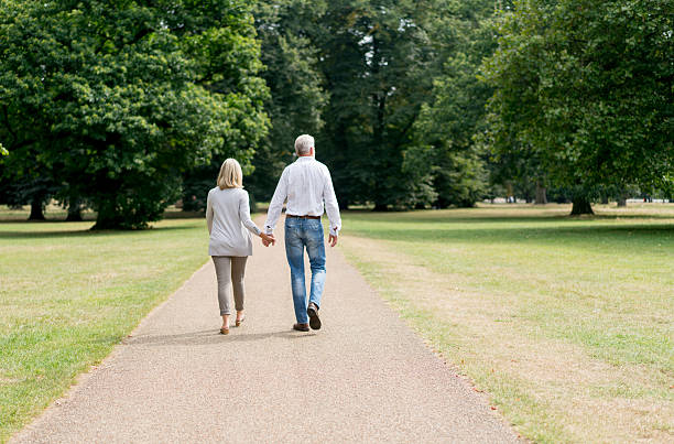 photo of a man and woman walking hand in hand in a park