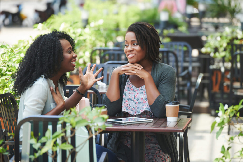 Two women smiling and talking together at an outdoor table