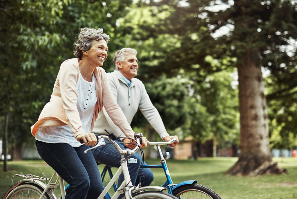 Older couple riding bicycles together outdoors