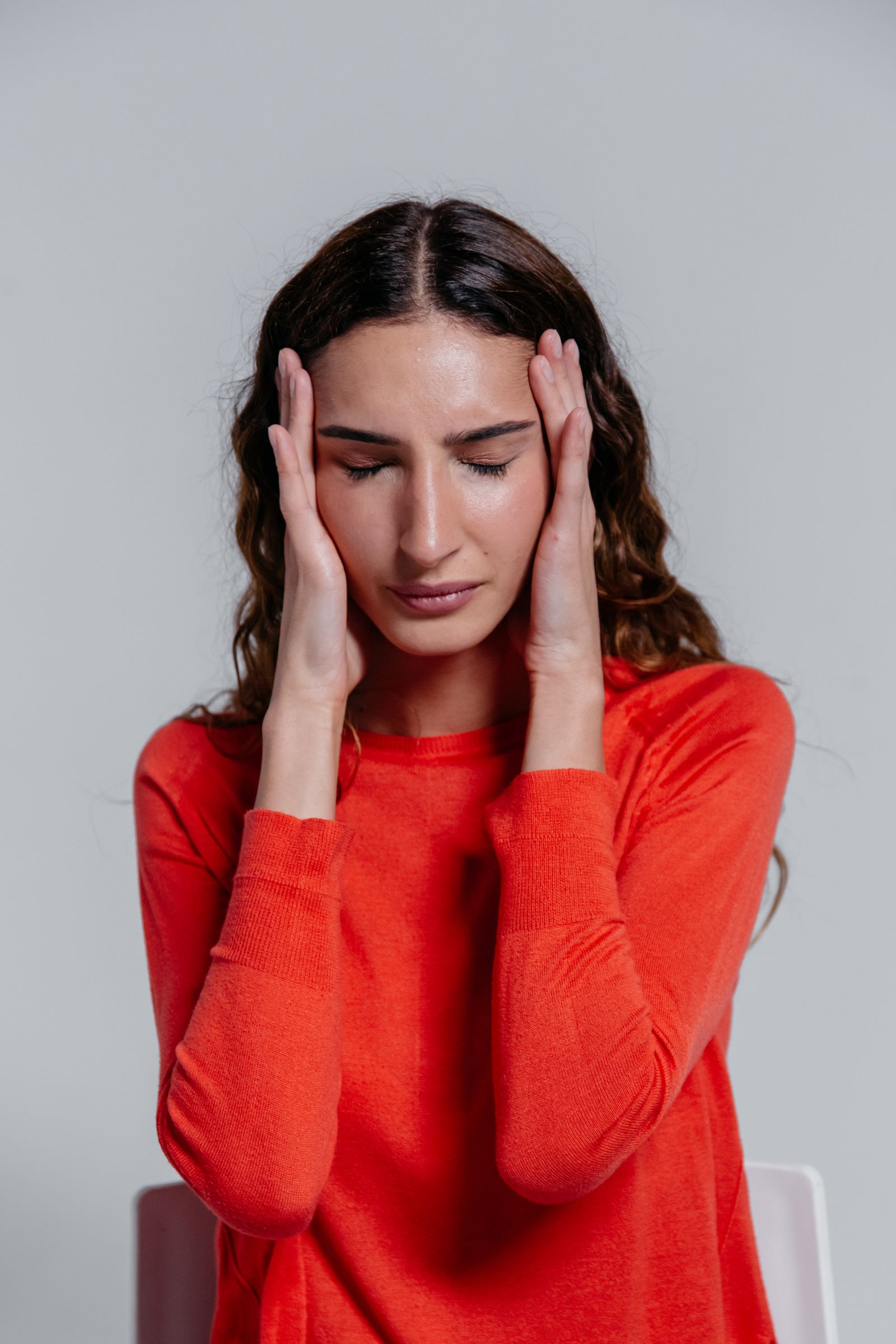 Professional-looking woman holding her head with brain fog and headache despite appearing outwardly healthy