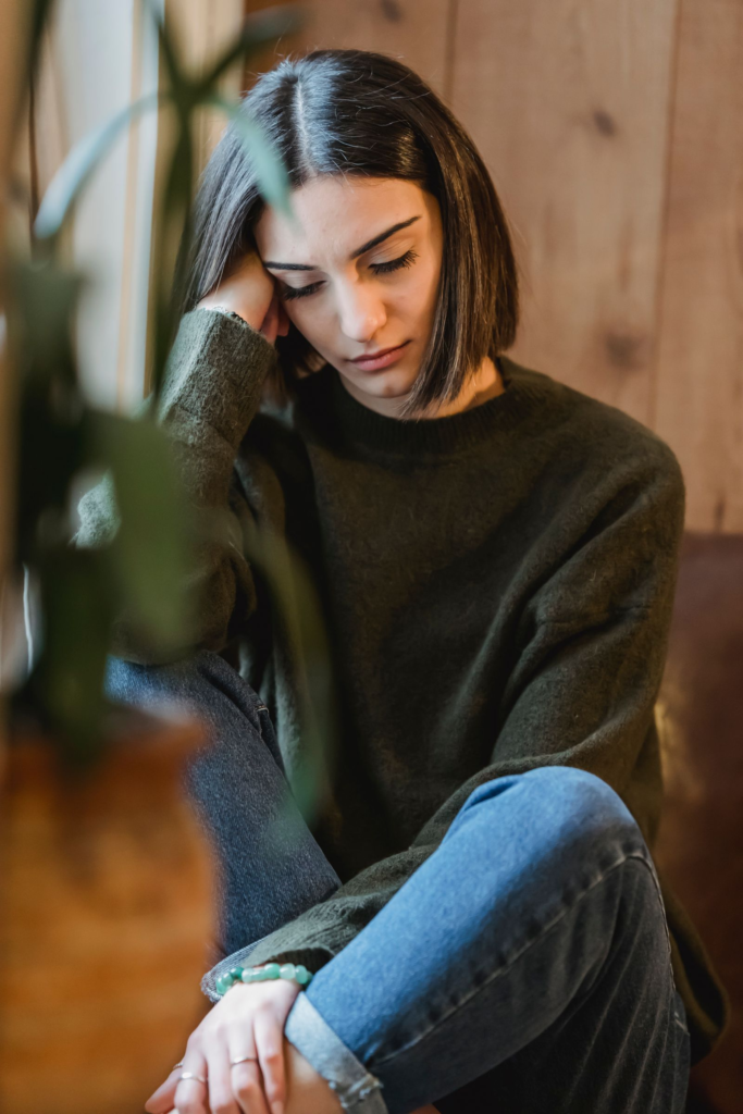 Woman who looks healthy on the outside resting near a window while dealing with invisible chronic fatigue